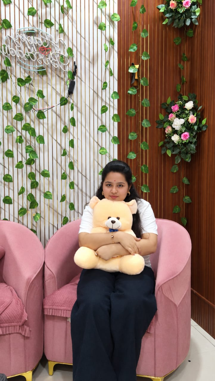 Divya smiling with a teddy bear at the birthday setup
